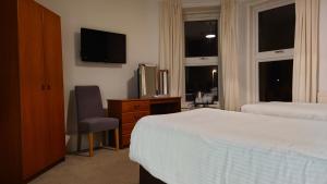 a bedroom with a bed and a tv and a chair at Corner Hotel in Carnoustie