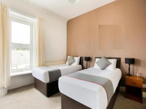 a bedroom with two beds and a window at Corner Hotel in Carnoustie