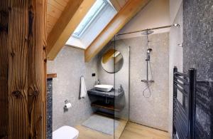 a bathroom with a glass shower with a sink at Apartmany Demänovka Jasna in Belá