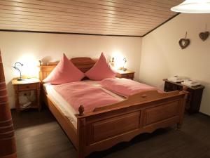 a bedroom with a wooden bed with pink pillows at Ferienwohnung - Haus Monika in Philippsreut