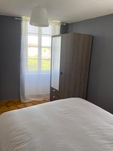 a bedroom with a white bed and a window at Charmant T2 au 1er dans résidence avec parc arboré in Saint-Pierre-le-Moûtier