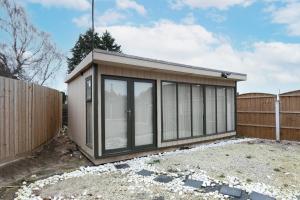 un pequeño cobertizo con puertas de cristal en una valla en Nottingham Top Serviced Home - Chayil Experts, en Nottingham