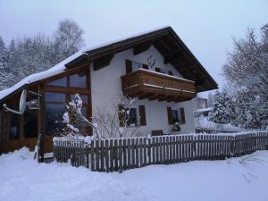 a house with a fence in the snow at Ferienwohnung - Haus Monika in Philippsreut