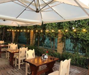 un patio con mesas y sillas bajo una sombrilla blanca en Golden Lion Hotel en Boryspilʼ