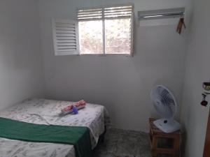 a bedroom with a bed and a fan and a window at Quarto Bem vindo in João Pessoa