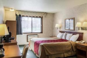 a hotel room with a bed and a desk with a phone at Econo Lodge North in Sioux Falls