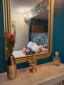 1 dormitorio con 1 cama con espejo y un jarrón con flores en La Belle Epoque, en Cournon-dʼAuvergne