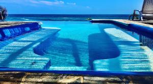een blauw zwembad met de oceaan op de achtergrond bij Casa Obe in Yolina
