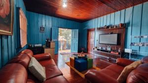 sala de estar con sofás de cuero y TV en Pousada Meu Paraiso en Foz de Iguazú