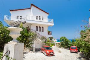 una casa blanca con dos coches aparcados delante de ella en Tassos & Marios Apartments II, en Alikanas