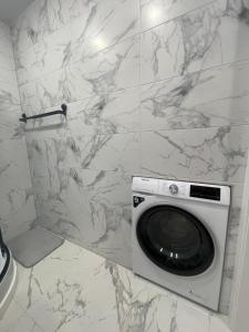 a washing machine in a bathroom with a marble wall at Livinga 1 kambario butas centre in Mažeikiai