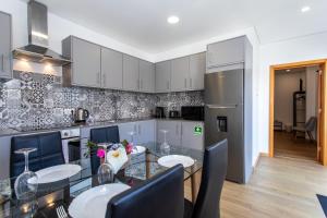 a kitchen with a table and chairs and a refrigerator at Carvão PDL Inn in Ponta Delgada