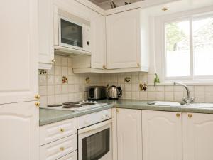 a white kitchen with white cabinets and a sink at Thirlmere Suite in Thirlmere