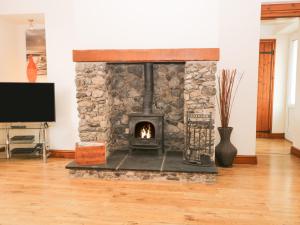 a stone fireplace in a living room with a tv at Fernleigh Cottage in Holker