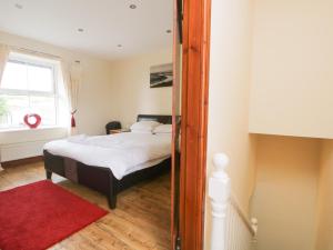 Schlafzimmer mit einem Bett und einem roten Teppich in der Unterkunft Fernleigh Cottage in Holker