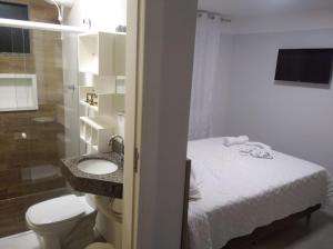 a bathroom with a bed and a sink and a toilet at Pousada Sol e Descanso in Arraial do Cabo