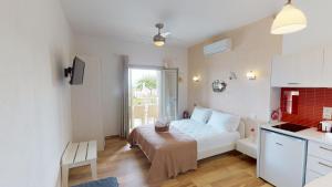 a small bedroom with a white bed and a kitchen at Studios Yalos in Chorefto