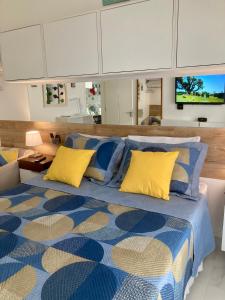 a bedroom with a bed with blue and yellow pillows at Guarujá La Plage Pitangueiras in Guarujá