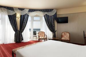 a bedroom with a bed and two chairs and a window at Lazur Beach by Stellar Hotels, Adler in Adler