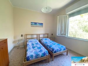 two beds in a room with a window at TamarHouse Sperlonga Casa Noemi in Sperlonga