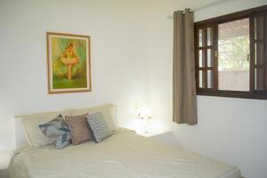 1 dormitorio con 1 cama con ventana y una foto en Casa das Orquídeas, en Arraial do Cabo