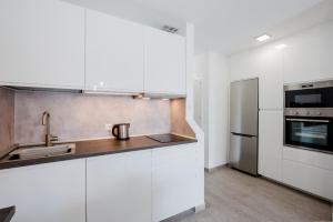 uma cozinha com armários brancos e um frigorífico de aço inoxidável em El Beril 82, Tenerife em Adeje