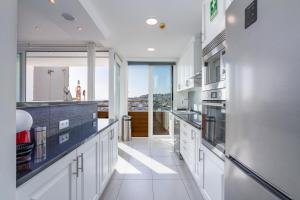 uma cozinha com armários brancos e uma grande janela em Clube do Monaco em Albufeira