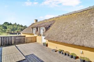 a thatch roofed house with a patio at Viking Surf Cottage in Klitmøller