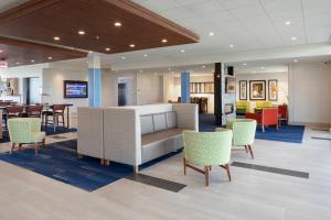 a lobby with a bed and chairs and tables at Holiday Inn Express & Suites - Bourbonnais East - Bradley by IHG in Bourbonnais