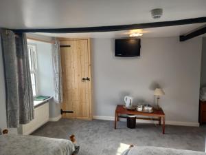 um quarto com uma cama, uma mesa e uma televisão em The Harp Inn em Glasbury