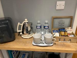 een tafel met twee koffiekopjes en een waterkoker bij The Lodge in Little Clacton