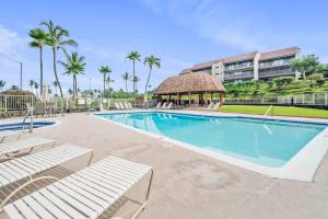 a swimming pool with lounge chairs and a building at Newly Renovated Condo Stand Up Paddle Boards Included! in Kailua-Kona