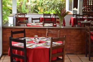 a restaurant with tables and chairs with red table cloth at Hotel La Chaumiere in Matoury