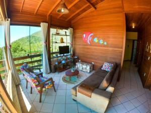 a living room with a couch and a tv and a balcony at Casa Vista Privilegiada: Piscina e Conforto in Garopaba