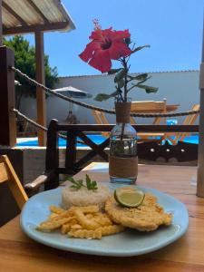 um prato de comida numa mesa com um vaso com uma flor em Costa Terral Hostel Beach Fun em Matinhos
