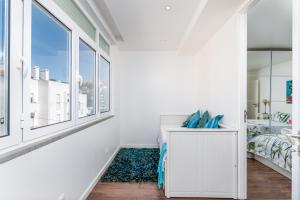 Habitación blanca con cama y ventana en Tilias Apartment at Estoril en Estoril