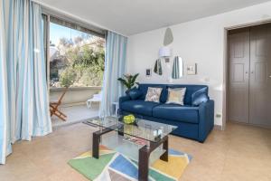 a living room with a blue couch and a glass table at Air-Conditioned Apartment With Sea View Furnished Terrace & Parking in Cap d'Ail