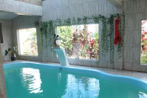 a swimming pool in a house with a large window at Pousada Aconchego da Valdirene in Lavras Novas