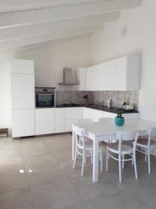 トッレ・グランデにあるCasa Toniaの白いテーブルと椅子のある白いキッチン