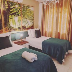 a room with two beds with a towel shaped like a stuffed animal at La Maison Brasiliana B&B in Foz do Iguaçu +47 photos