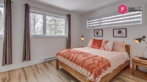 a bedroom with a bed and two windows at La Fleur Urbaine de Portneuf : 2.5 bathrooms, Hot tub, Sauna and Pool in Pont-Rouge