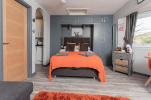 a bedroom with a large bed with an orange blanket at Soay@Knock View Apartments, Sleat, Isle of Skye in Teangue