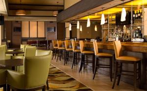 um restaurante com um bar com cadeiras castanhas e verdes em Sonesta Hotel Gwinnett Place Atlanta em Duluth