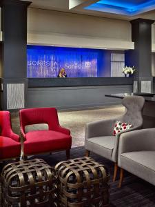 a lobby with red chairs and a large screen at Sonesta Hotel Gwinnett Place Atlanta in Duluth