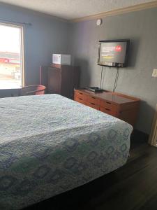 a bedroom with a bed and a flat screen tv at Surf Motel and Apartments in Galveston
