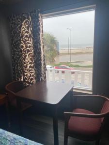 a table and chairs and a window with a view of the beach at Surf Motel and Apartments in Galveston