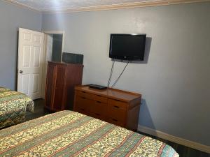 a hotel room with two beds and a tv on the wall at Surf Motel and Apartments in Galveston