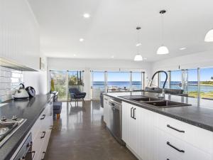 a kitchen with white cabinets and a view of the ocean at Catalina in Culburra Beach