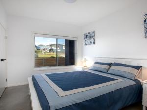 Un dormitorio con una cama grande y una ventana. en Catalina, en Culburra Beach