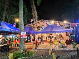 un restaurant avec des parasols et des tables violets la nuit dans l'établissement Bell Family Suite @Sepang Kota Warisan KLIA, à Sepang